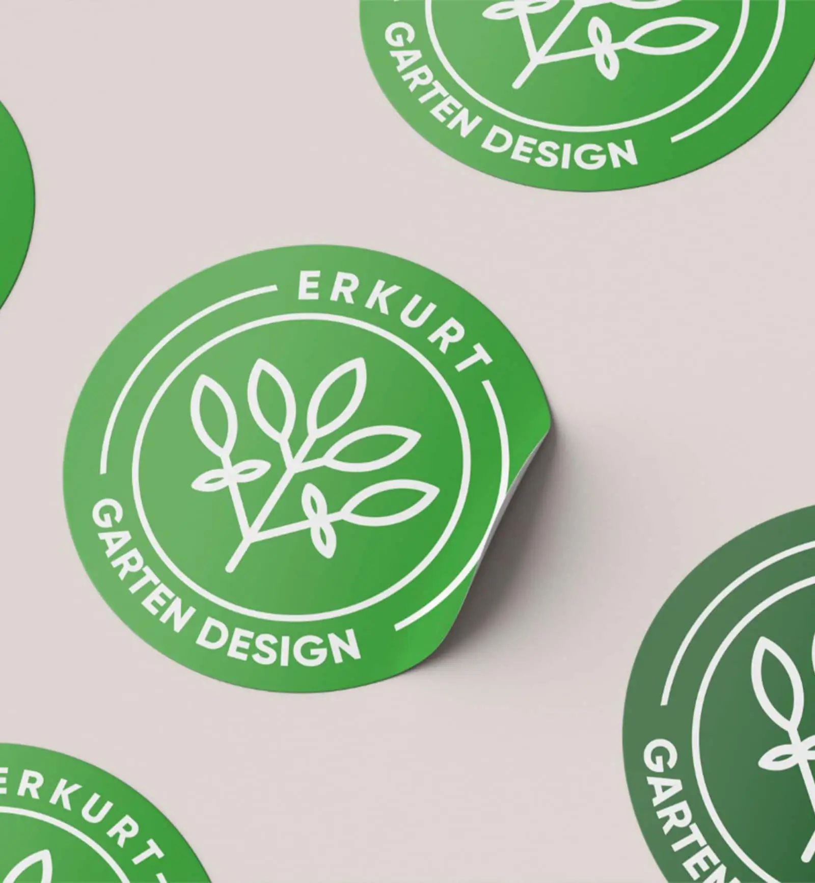 Runde Aufkleber von Erkurt Gartengestaltung mit dem grünen Logo, die die Markenidentität repräsentieren.